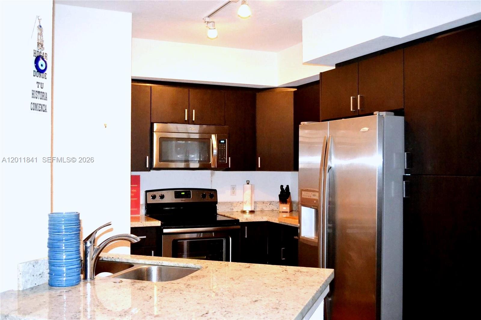 A kitchen features dark wood cabinets, stainless steel appliances, and granite countertops — 1830 Radius Dr # 317, Hollywood FL 33020, HOLLYWOOD, FL