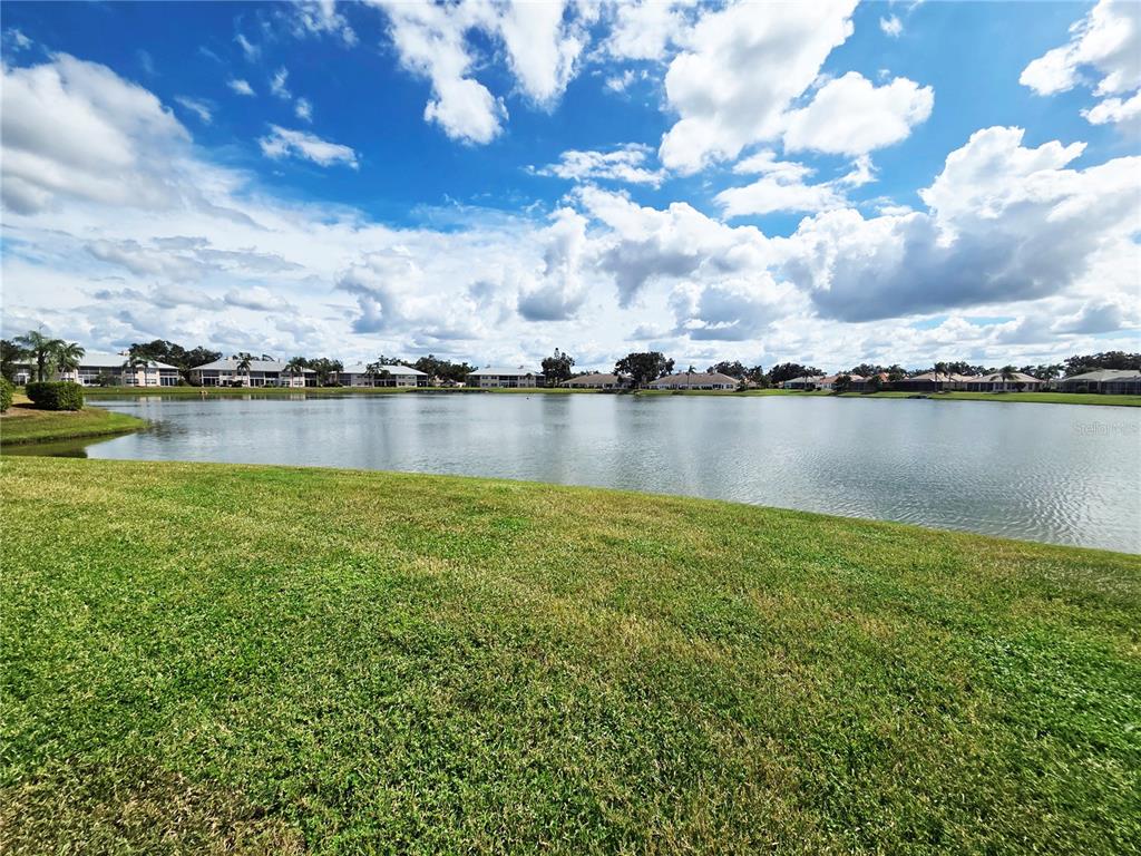 A grassy lawn overlooks a large lake surrounded by residential buildings under a cloudy sky — 4207 CADDIE DRIVE E UNIT 104, BRADENTON, FL