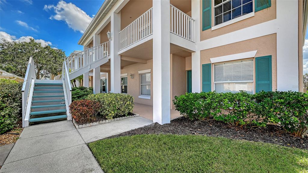 An exterior view of a two-story building featuring a staircase leading to an upper balcony — 4207 CADDIE DRIVE E UNIT 104, BRADENTON, FL