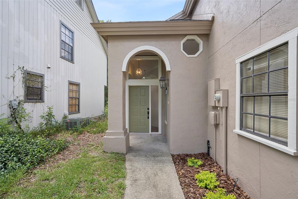 An exterior view of a home entrance with a green door and arched entryway — 1866 SUMMIT CHASE AVENUE, APOPKA, FL