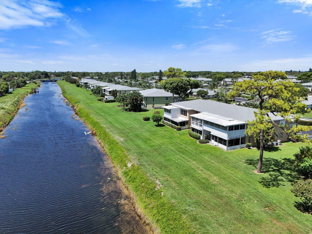 An aerial view of a multi-story apartment building situated along a canal and grassy lawn — 1050 Citrus Way # 203, Delray Beach FL 33445, DELRAY BEACH, FL