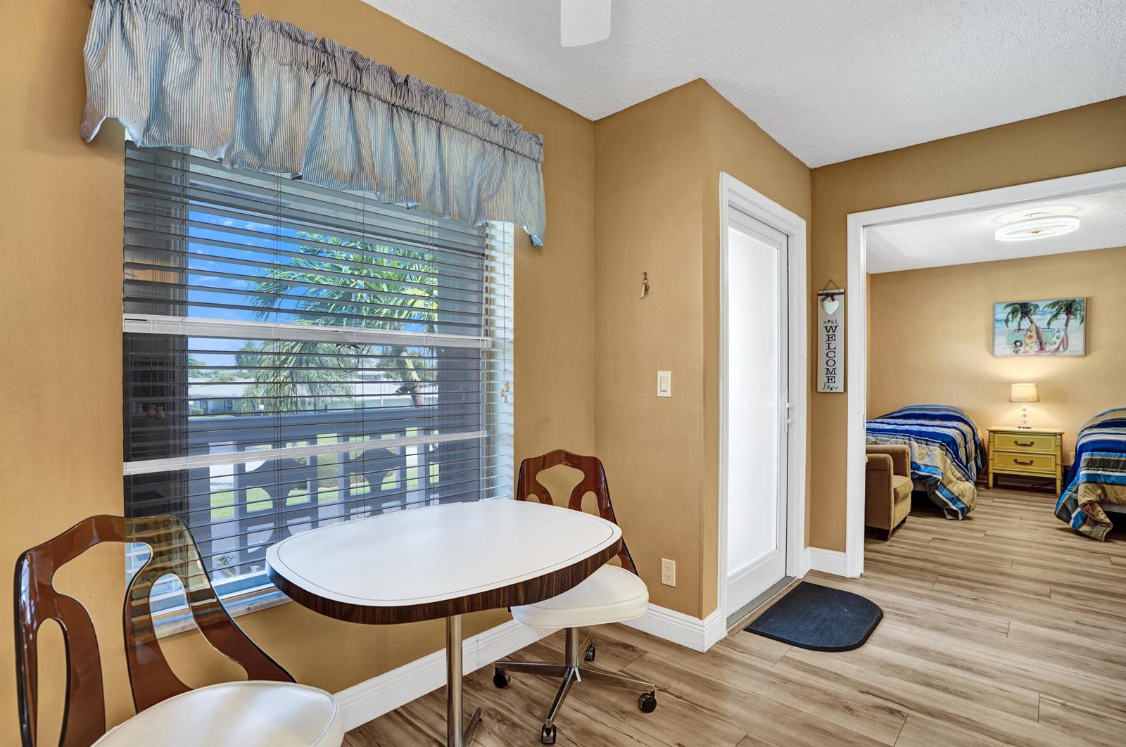 A dining area with a small table and chairs leads into a bedroom with twin beds — 1050 Citrus Way # 203, Delray Beach FL 33445, DELRAY BEACH, FL