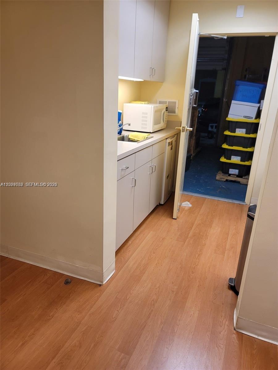 A small kitchenette with white cabinets and a microwave sits next to an open doorway — 12905 SW 132nd St # 6, Miami FL 33186, MIAMI, FL
