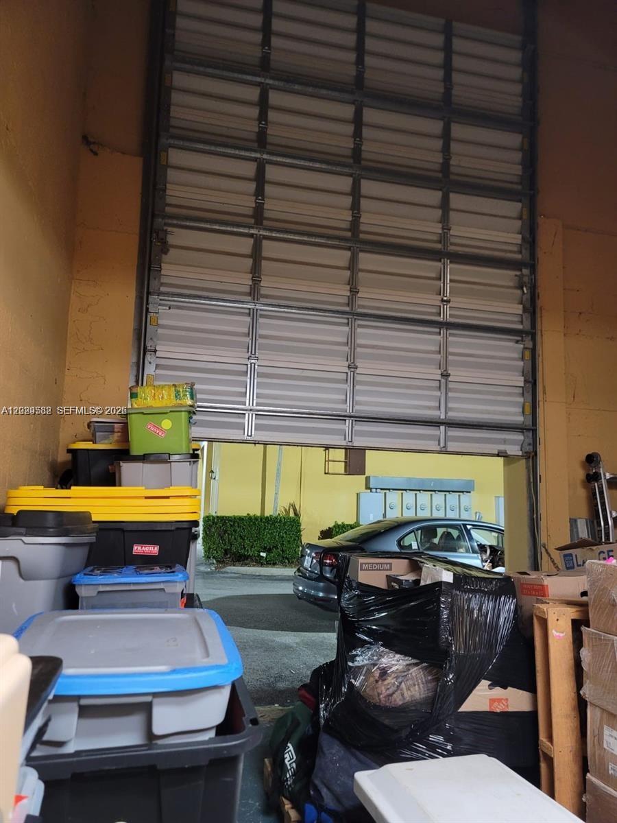 A garage with a partially open roll-up door and stacked storage bins — 12905 SW 132nd St # 6, Miami FL 33186, MIAMI, FL
