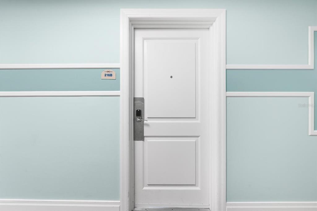 A white door with a silver electronic lock is centered on a light blue wall — 536 BAHIA BEACH BOULEVARD UNIT 233C, RUSKIN, FL