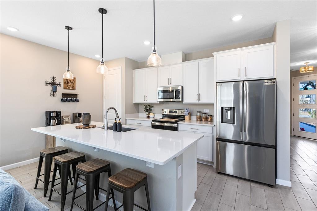 A modern kitchen features white cabinetry, stainless steel appliances, a large island, and bar stools — 4160 SOUTHERN VISTA LOOP, ST CLOUD, FL