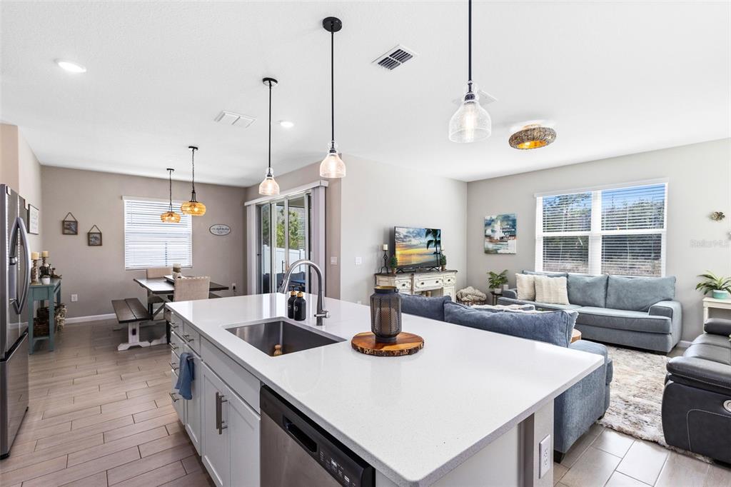 A kitchen island with a sink overlooks an open-concept living and dining area — 4160 SOUTHERN VISTA LOOP, ST CLOUD, FL
