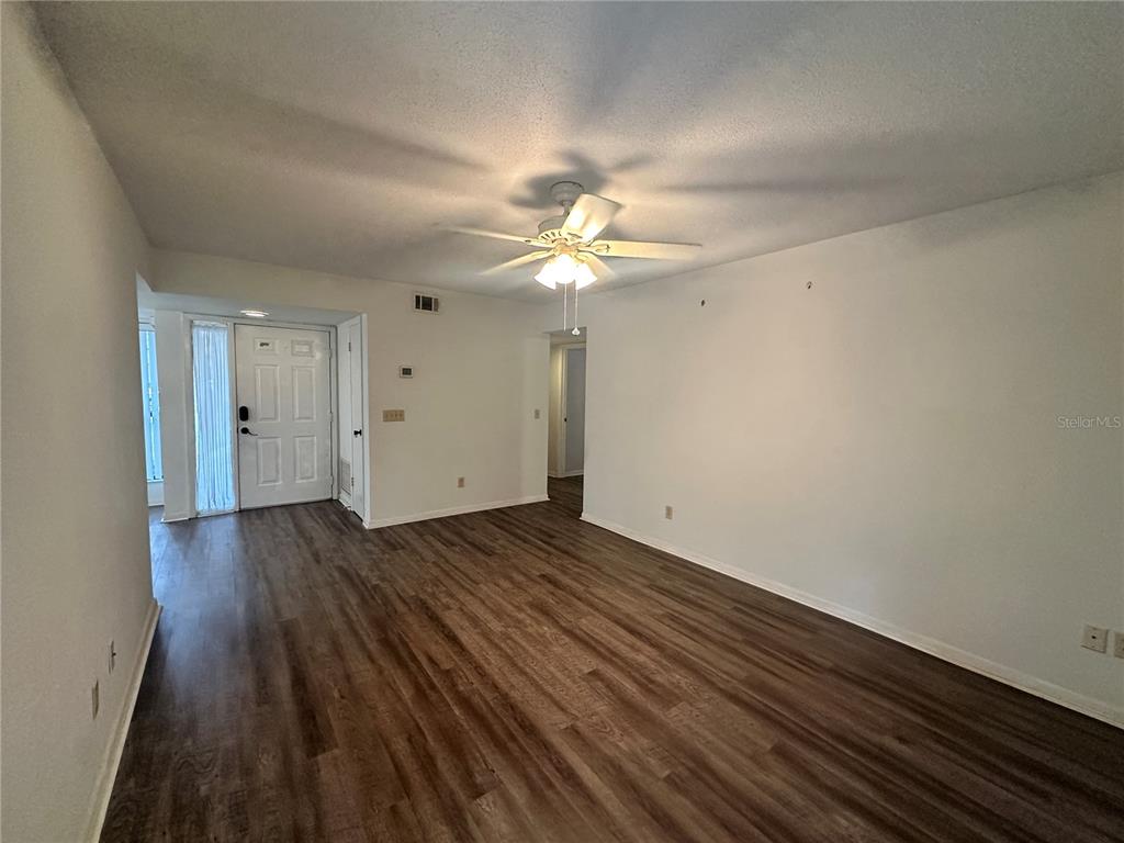 An empty living room features wood-look flooring, white walls, and a ceiling fan — 13 SURREY COURT UNIT 13, PALM COAST, FL