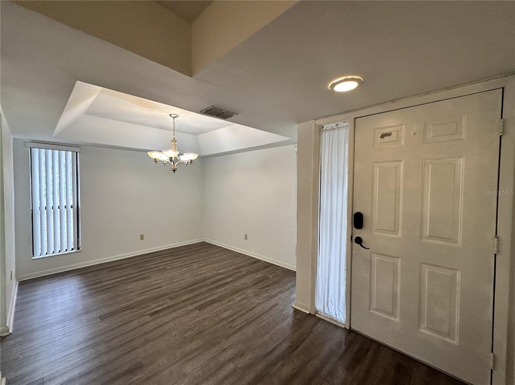 An entryway leads into a dining room with a tray ceiling and wood-look flooring — 13 SURREY COURT UNIT 13, PALM COAST, FL