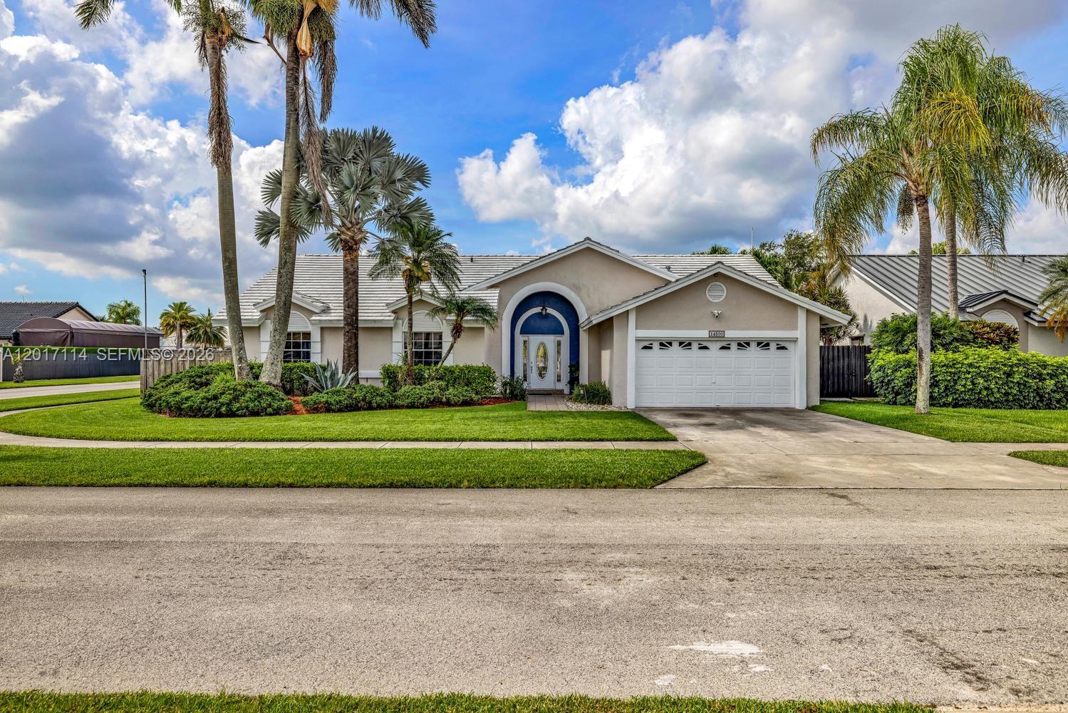 A single-story house with a white garage, arched entryway, and palm trees in the front yard — 14500 SW 161st St, Miami FL 33177, MIAMI, FL