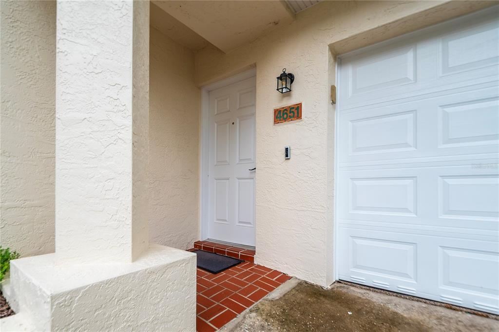 The exterior view shows a white front door, a garage door, and a brick entryway — 4651 MIRABELLA COURT, ST PETE BEACH, FL