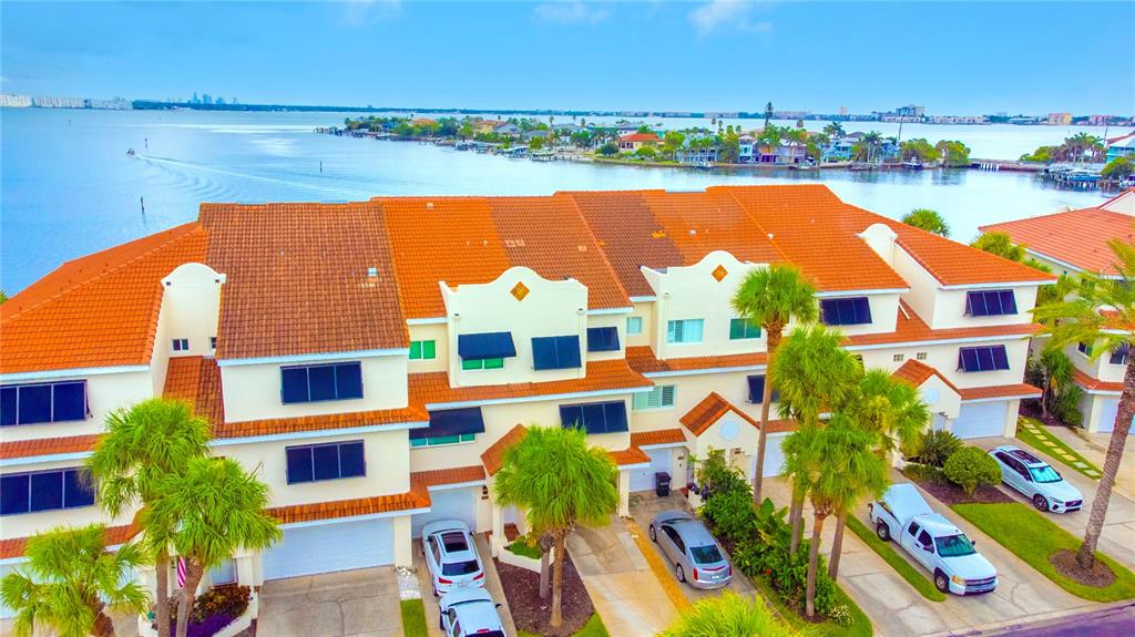 An aerial view of a multi-story townhouse complex with orange tile roofs and palm trees — 4651 MIRABELLA COURT, ST PETE BEACH, FL