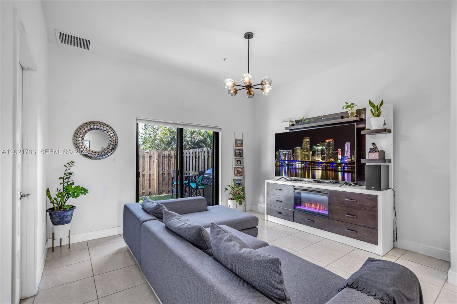 A living room features a grey sectional sofa, a media console with a fireplace, and sliding doors — 8015 NW 104th Ave # 3, Doral FL 33178, DORAL, FL