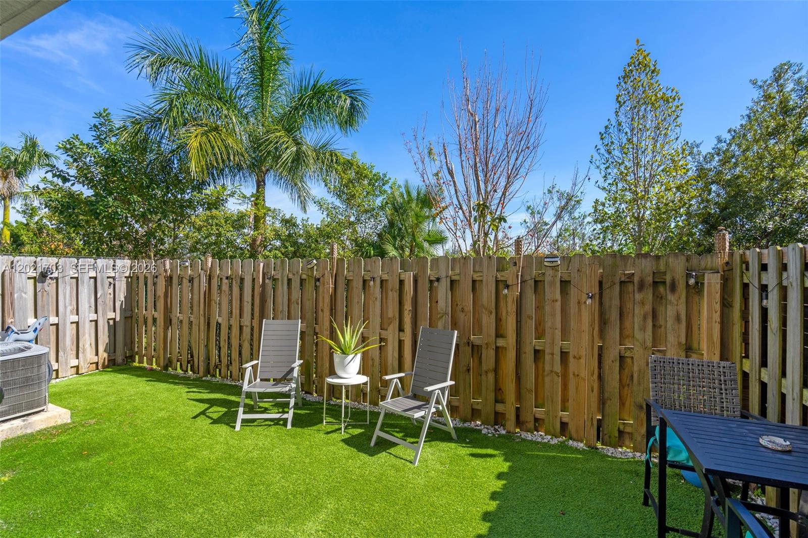 A fenced backyard features artificial turf, two chairs, a small table, and a dining set — 8015 NW 104th Ave # 3, Doral FL 33178, DORAL, FL
