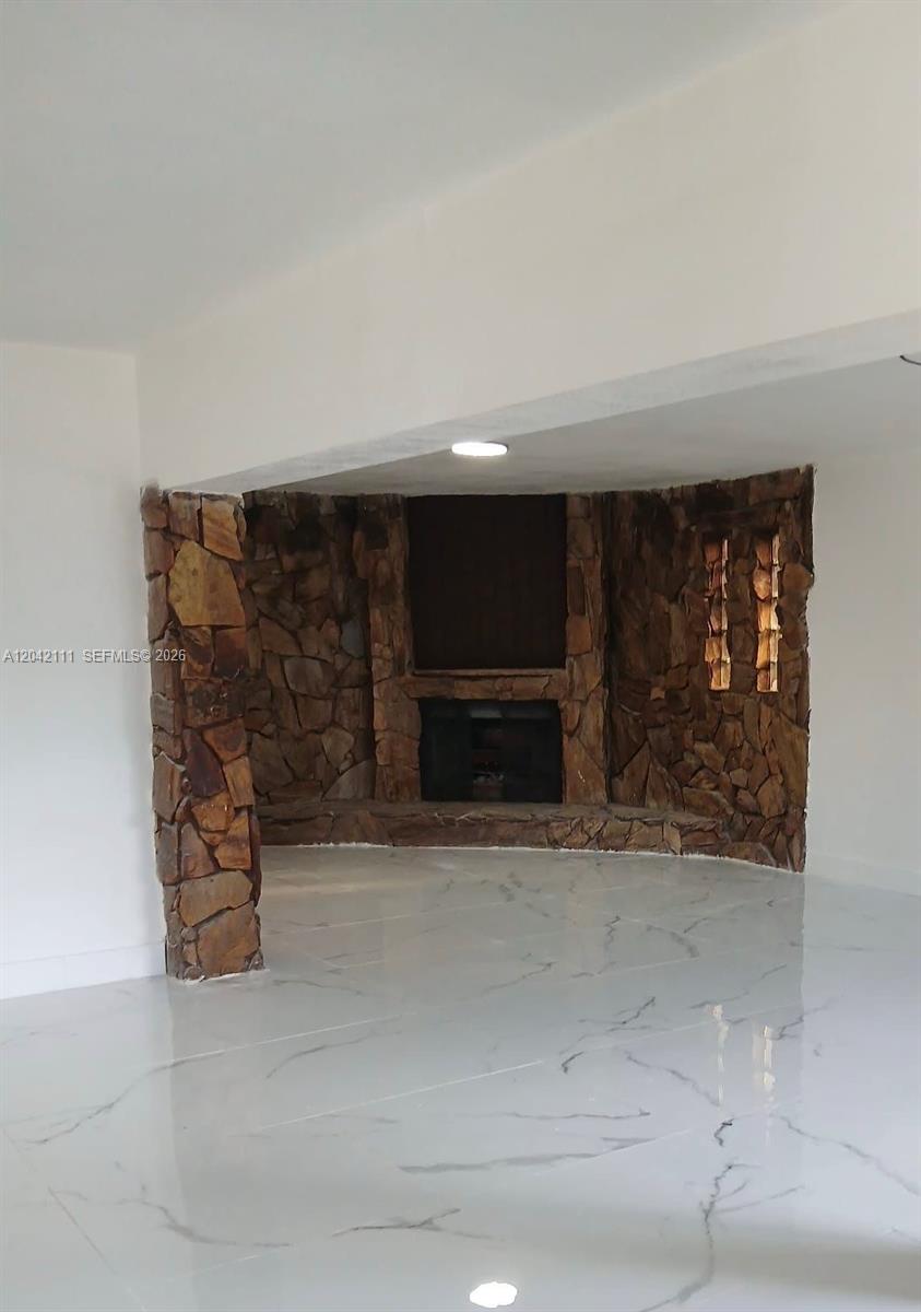 A room features a stone fireplace wall and white marble-look tile flooring — 560 NW 188th St # 1, Miami Gardens FL 33169, MIAMI GARDENS, FL
