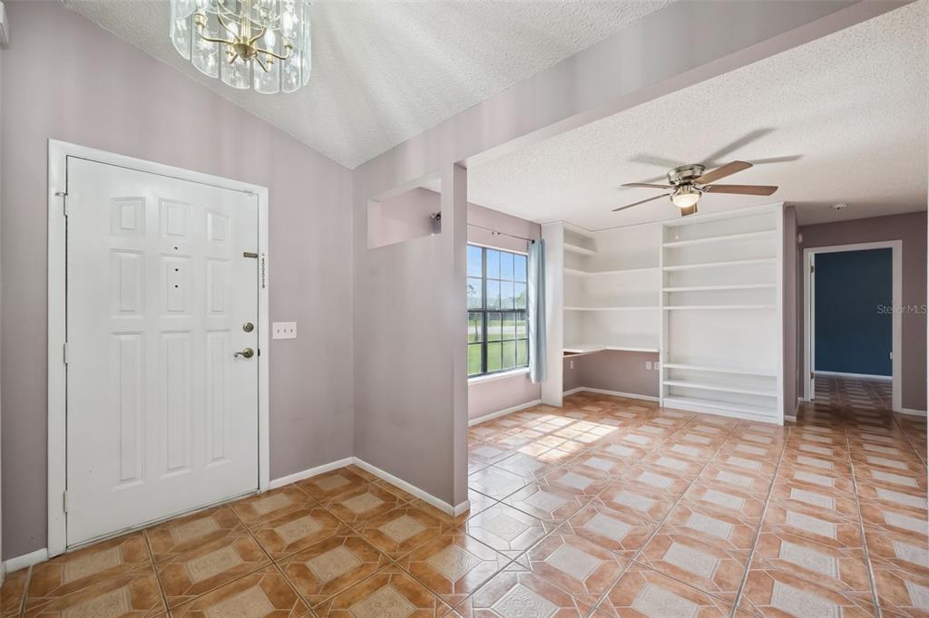 An entryway with tile flooring leads to a room featuring built-in white shelving and desks — 2620 E DORCHESTER DR, DELTONA, FL