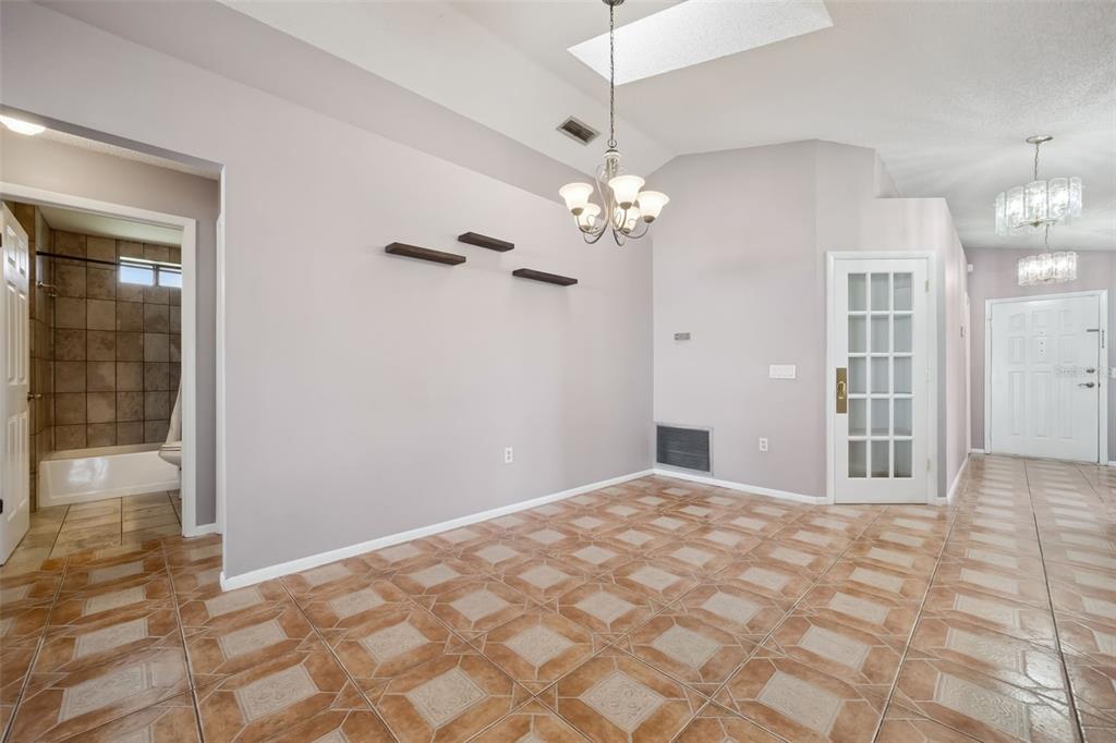 A dining area features tile flooring, a chandelier, floating shelves, and a glass-paneled door — 2620 E DORCHESTER DR, DELTONA, FL