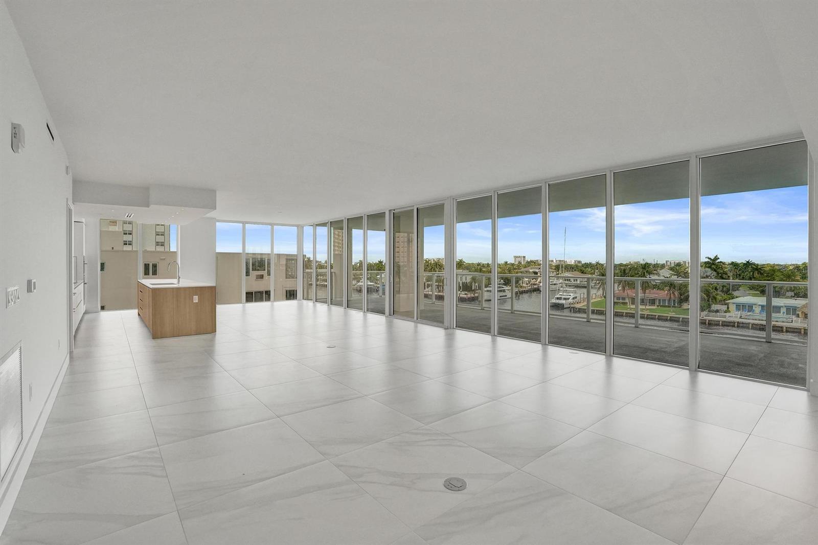 A bright, open-concept living area features large floor-to-ceiling windows, white tile flooring, and a kitchen — 407 N Riverside Drive # 401, Pompano Beach FL 33062, POMPANO BEACH, FL
