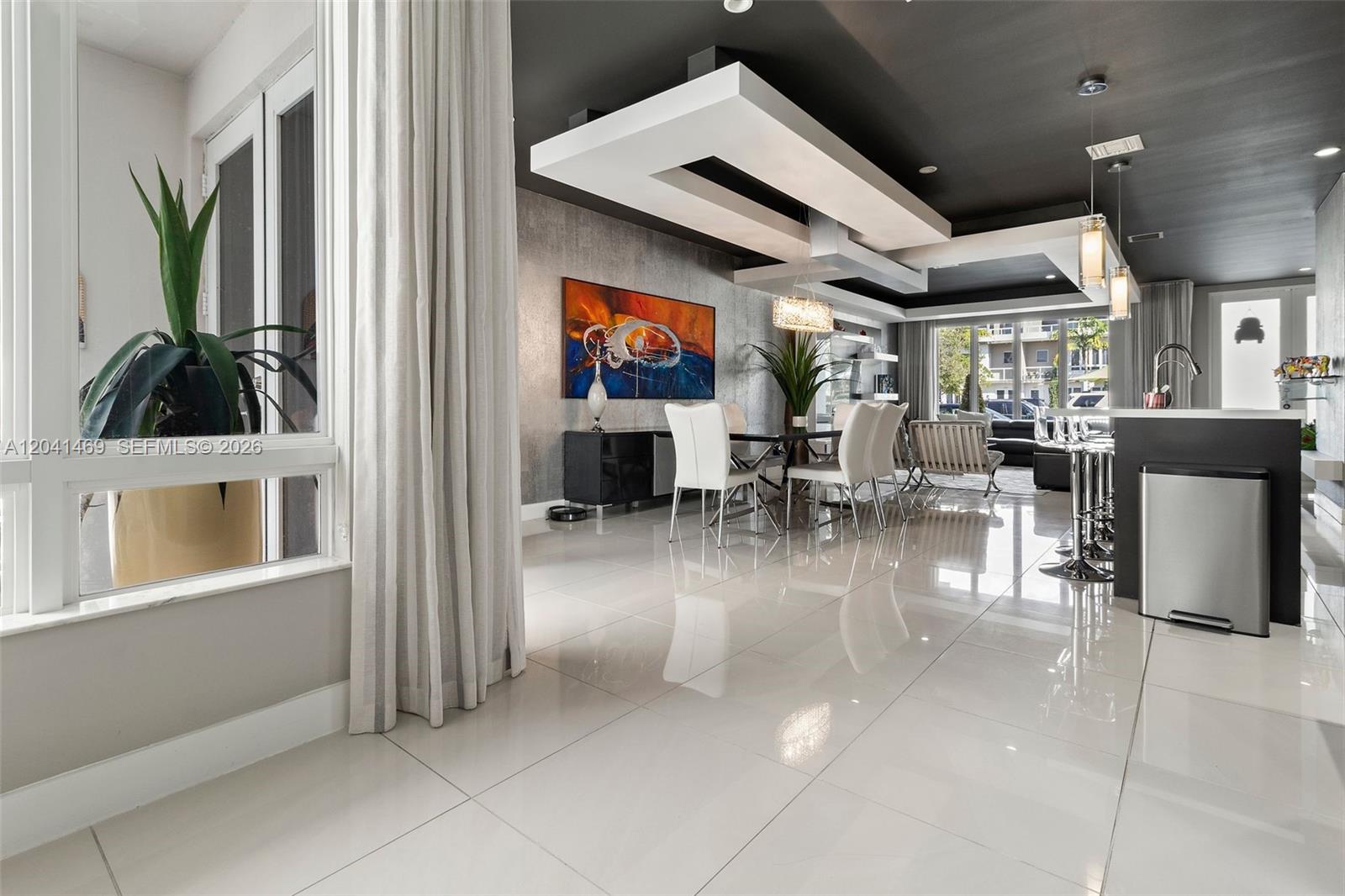 A modern open-concept dining and kitchen area features glossy tile floors and a dark ceiling — 6306 NW 104th Path, Doral FL 33178, DORAL, FL
