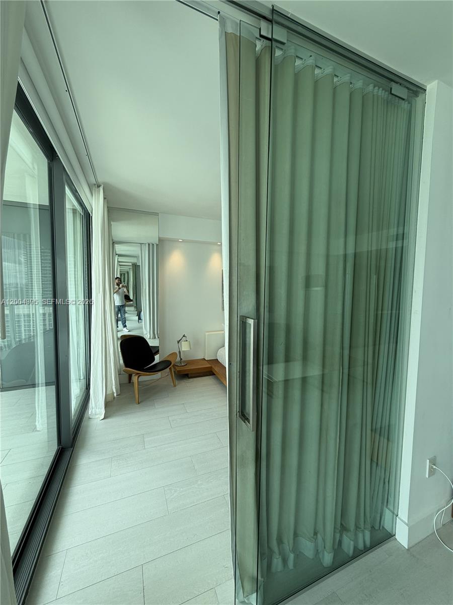A bedroom features light wood flooring, a glass sliding door, and a modern lounge chair — 460 NE 28th St # 2806, Miami FL 33137, MIAMI, FL
