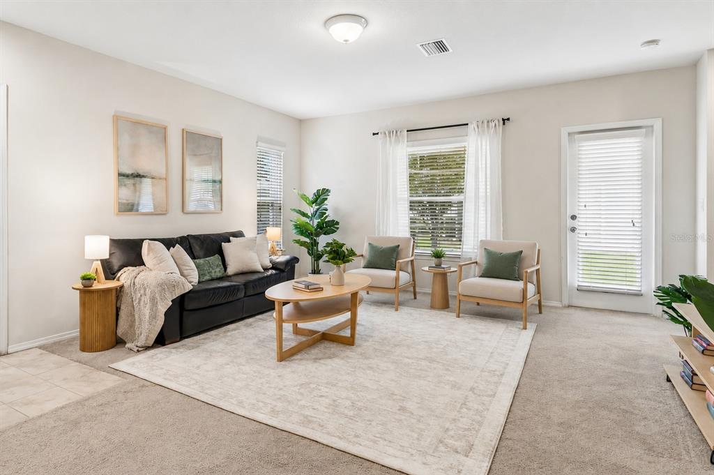A living room features a black sofa, two armchairs, a coffee table, and carpeted floors — 4741 CHATTERTON WAY, RIVERVIEW, FL