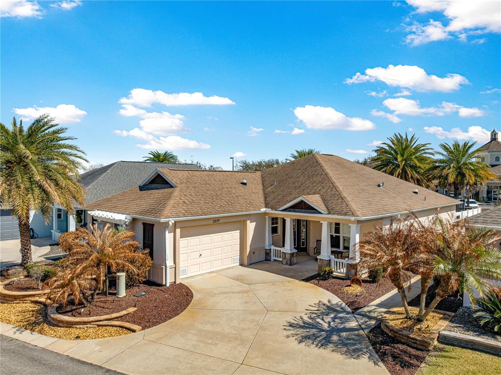 A single-story house with a tan exterior, brown roof, and palm trees in the front yard — 2859 RESMONDO ROAD, THE VILLAGES, FL