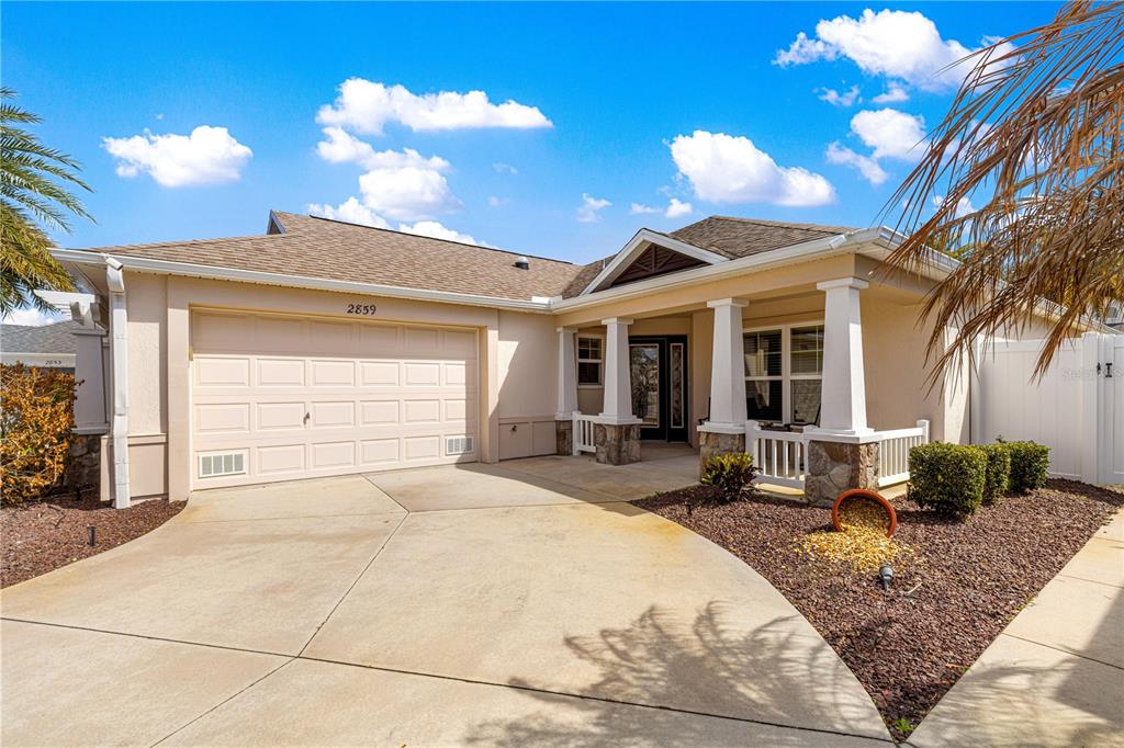 A single-story house with a beige stucco exterior, a two-car garage, and a covered porch — 2859 RESMONDO ROAD, THE VILLAGES, FL