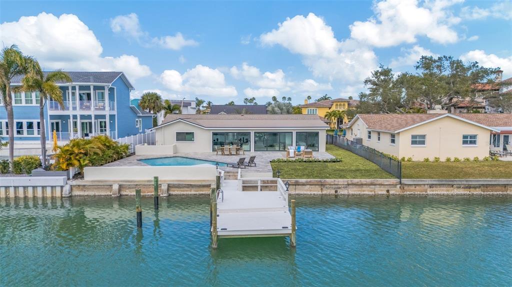 An aerial view shows waterfront homes with docks, swimming pools, and paved driveways — 825 116TH AVENUE, TREASURE ISLAND, FL