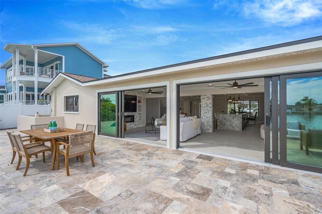 A covered entryway features a stone-based pillar, paver walkway, and a dark-framed glass front door — 825 116TH AVENUE, TREASURE ISLAND, FL