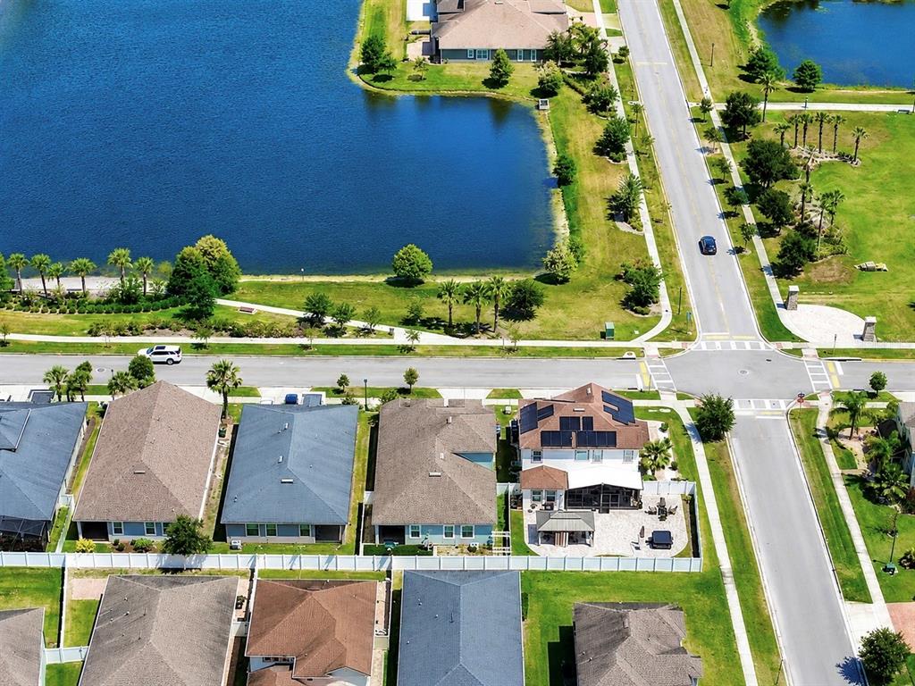 An aerial view shows a suburban neighborhood with houses, a lake, and intersecting roads — 2916 CHANTILLY AVENUE, KISSIMMEE, FL
