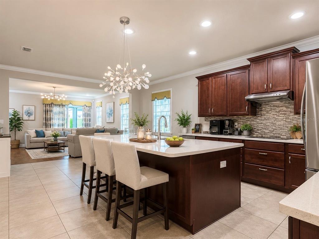 A kitchen with a large island and bar seating opens into a living room area — 2916 CHANTILLY AVENUE, KISSIMMEE, FL