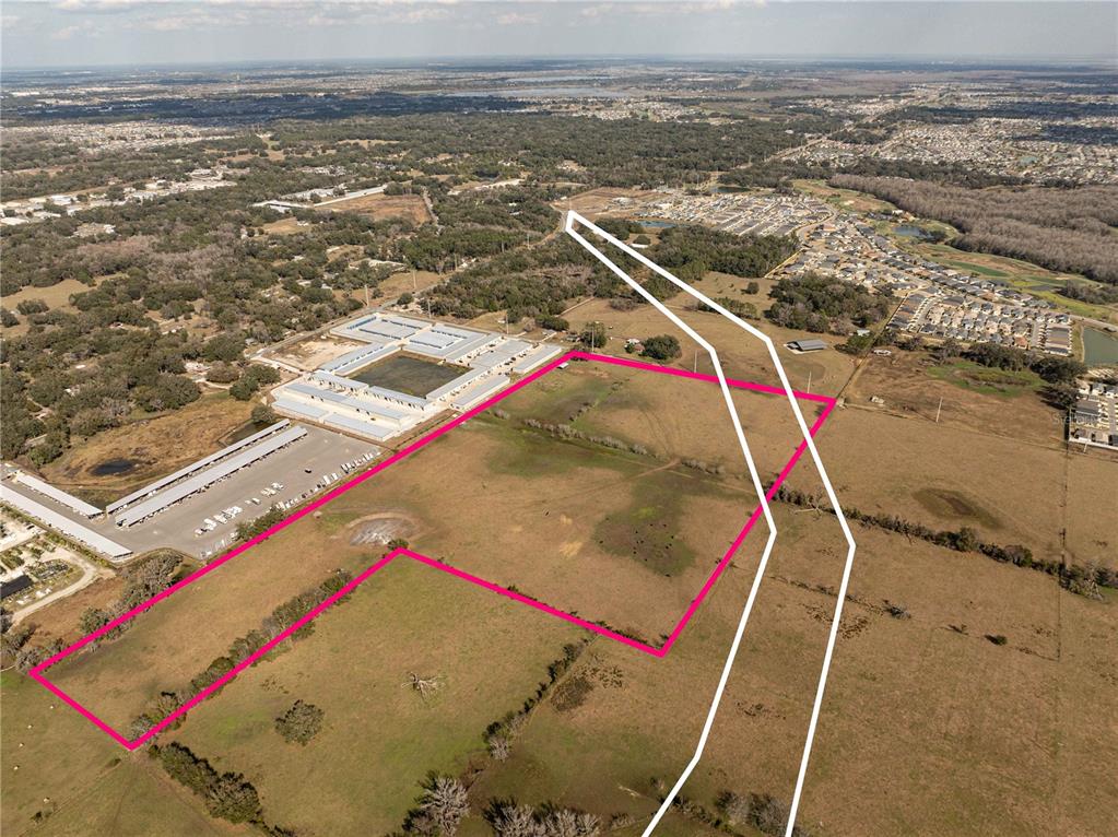 An aerial view shows a large, undeveloped grassy lot outlined in pink and white lines — CR 523, WILDWOOD, FL