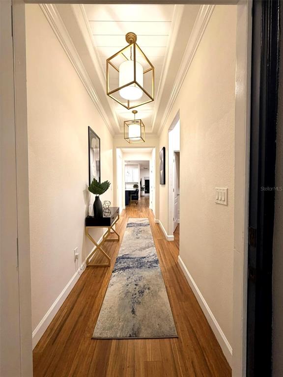 A hallway with wood floors, a runner rug, and two gold geometric pendant lights — 19311 PRAIRIE TREE PLACE, TAMPA, FL