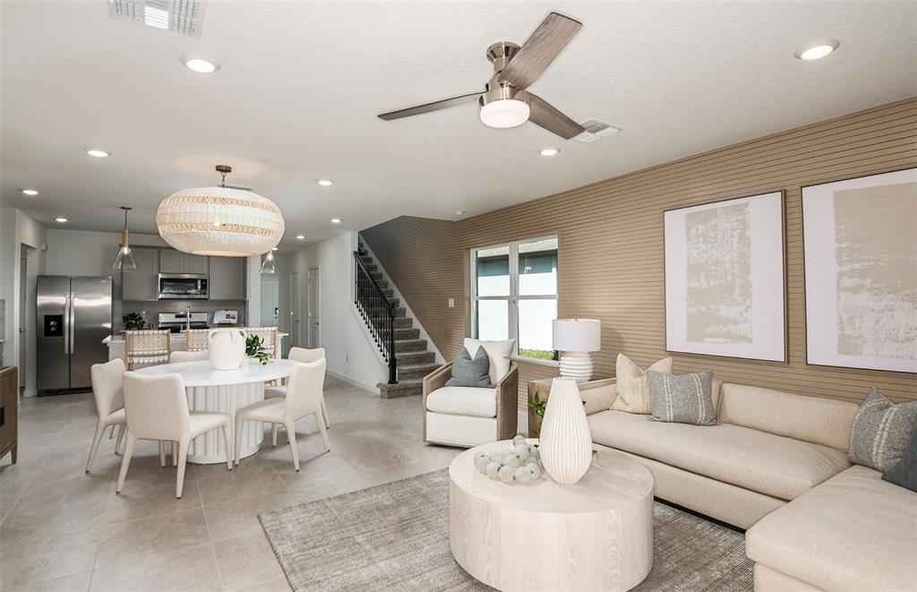 An open-concept living and dining area features a slatted accent wall and neutral furniture — 1391 ALLAGASH DRIVE, ZEPHYRHILLS, FL
