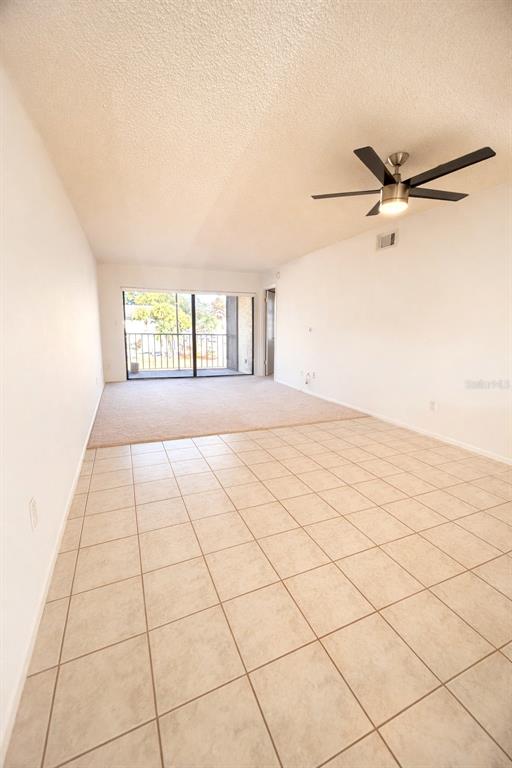 An interior view shows a living area with tile flooring, carpeted space, and a ceiling fan — 3244 CANDLE RIDGE DRIVE UNIT 202, ORLANDO, FL