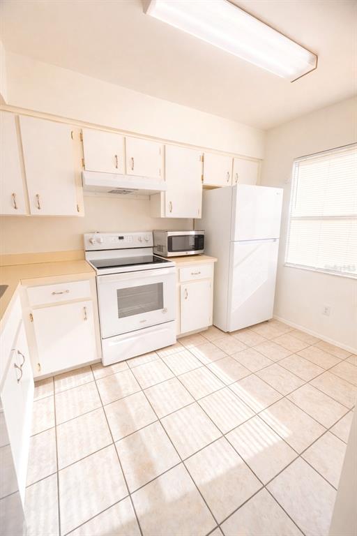 A kitchen features white cabinets, a white stove, a microwave, and a white refrigerator — 3244 CANDLE RIDGE DRIVE UNIT 202, ORLANDO, FL