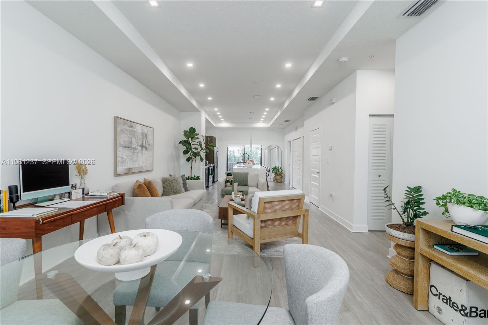 A bright, open-concept living and dining area features light wood flooring and white walls — 7831 NW 104th Ave # 32, Doral FL 33178, DORAL, FL