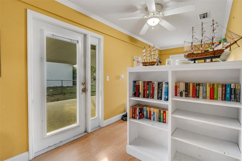 A room with yellow walls, wood-look flooring, a ceiling fan, and a white bookshelf — 202 SAINT LUCIE ROAD, WINTER HAVEN, FL
