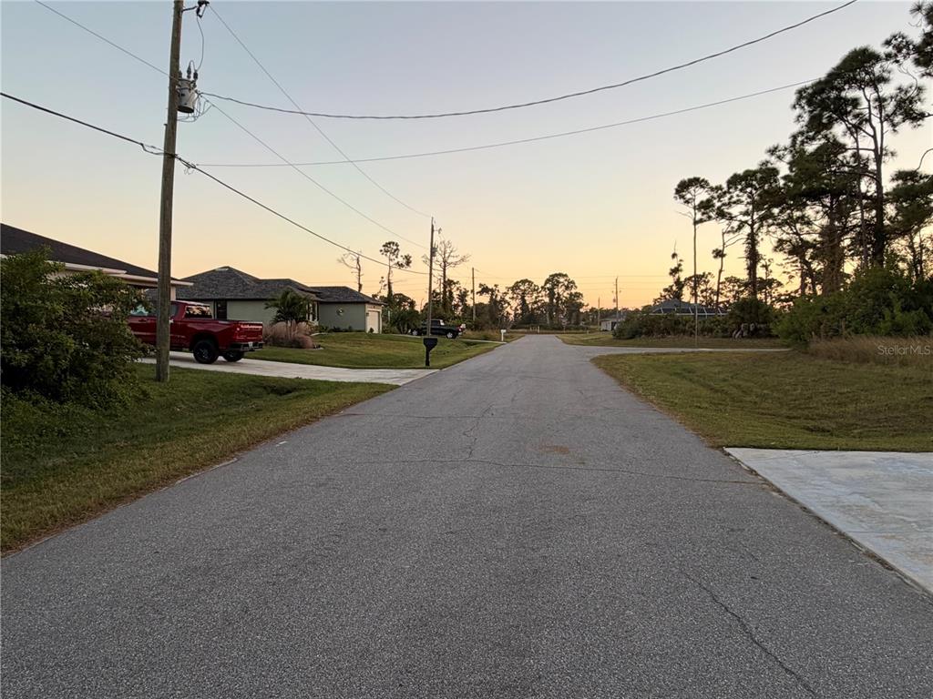 A paved residential street stretches toward the horizon under a clear sunset sky — 113 OPAL DR, ROTONDA WEST, FL