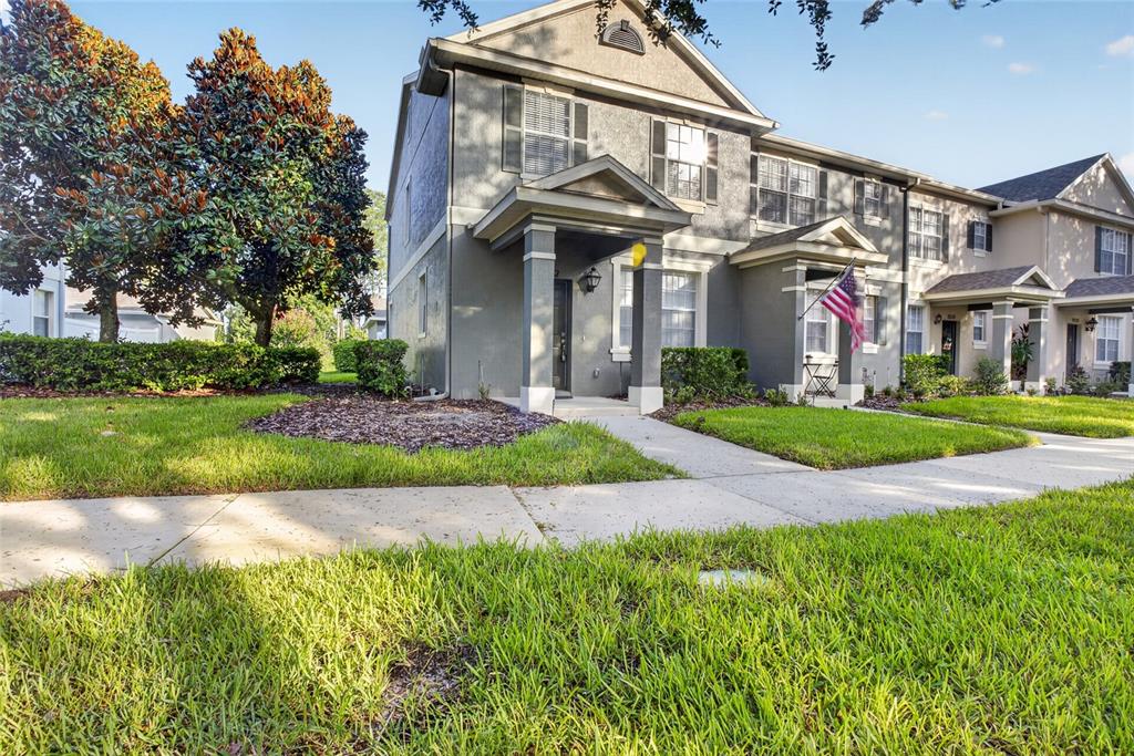 A two-story gray townhouse with a covered front porch and a small American flag — 8832 DANFORTH DRIVE, WINDERMERE, FL