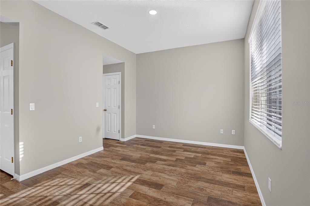 An empty room with light gray walls, wood-look tile flooring, and a large window — 8832 DANFORTH DRIVE, WINDERMERE, FL