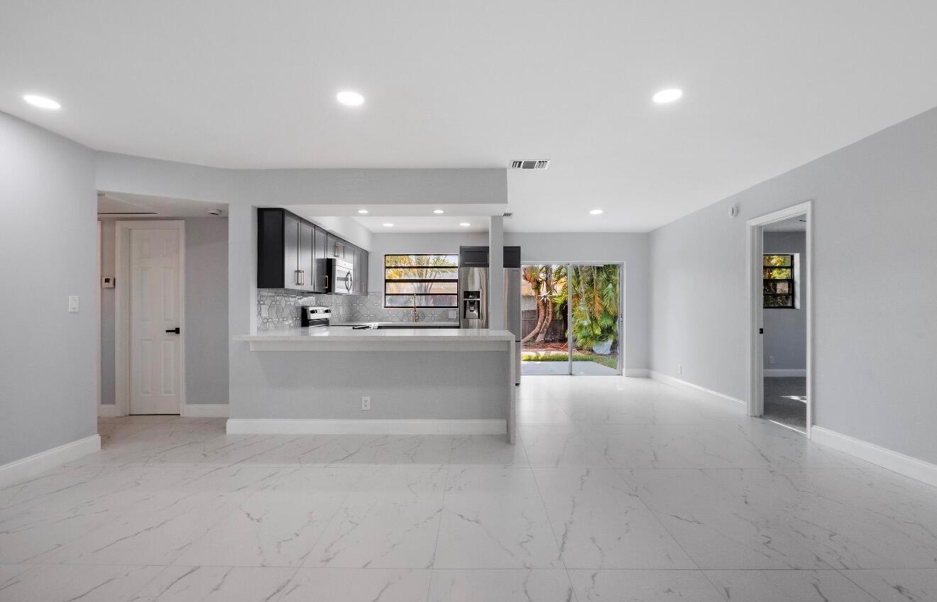 A bright, open-concept living area features white marble-look tile floors and a kitchen with dark cabinets — 1661 NW 1st Avenue, Pompano Beach FL 33060, POMPANO BEACH, FL
