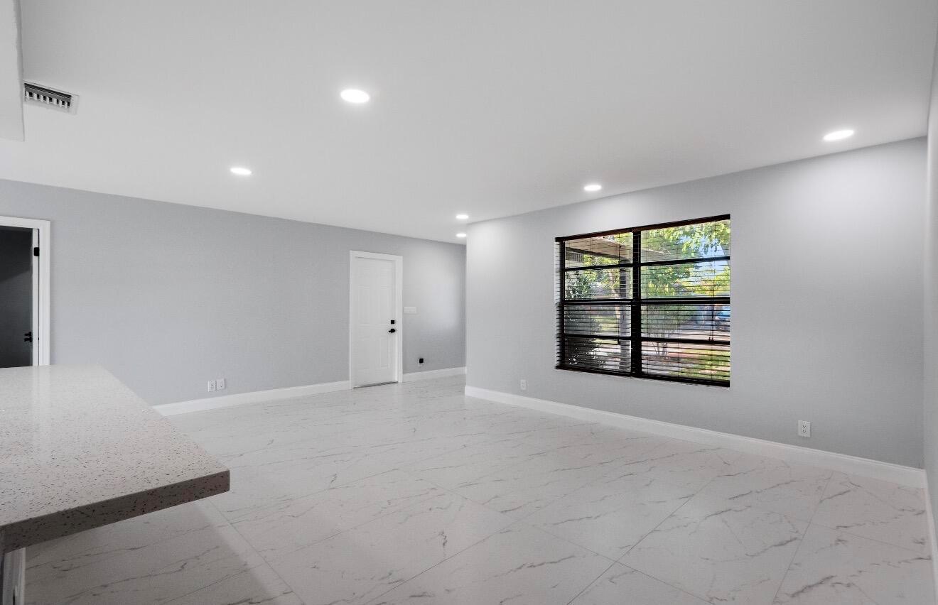 A bright, open-concept room features light gray walls, white marble-look tile flooring, and recessed lighting — 1661 NW 1st Avenue, Pompano Beach FL 33060, POMPANO BEACH, FL
