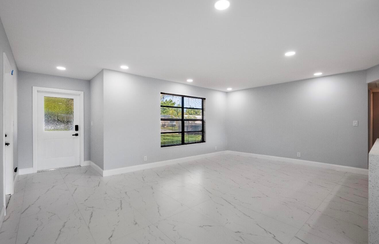 A bright, empty room features light gray walls, white marble-look tile flooring, and recessed lighting — 1661 NW 1st Avenue, Pompano Beach FL 33060, POMPANO BEACH, FL