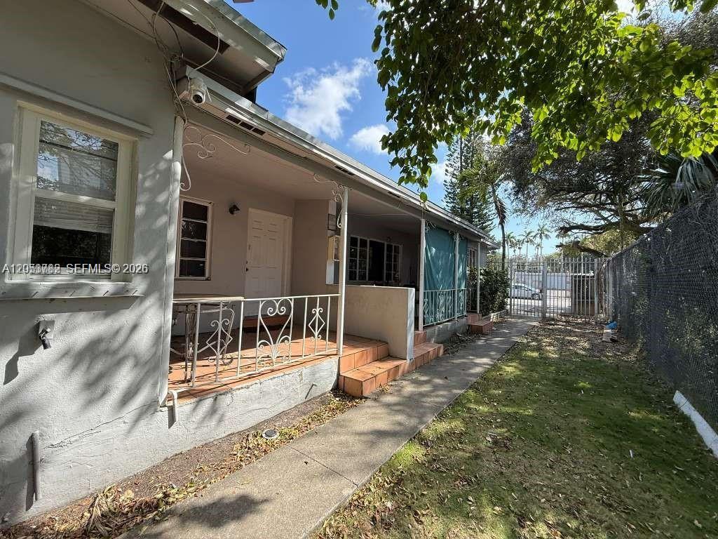 A concrete walkway leads to a covered porch with metal railings along a house exterior — MIAMI, FL