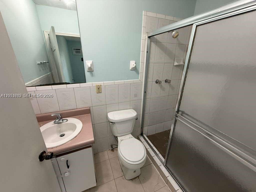 This bathroom features a pink vanity, a white toilet, and a glass-enclosed shower — MIAMI, FL