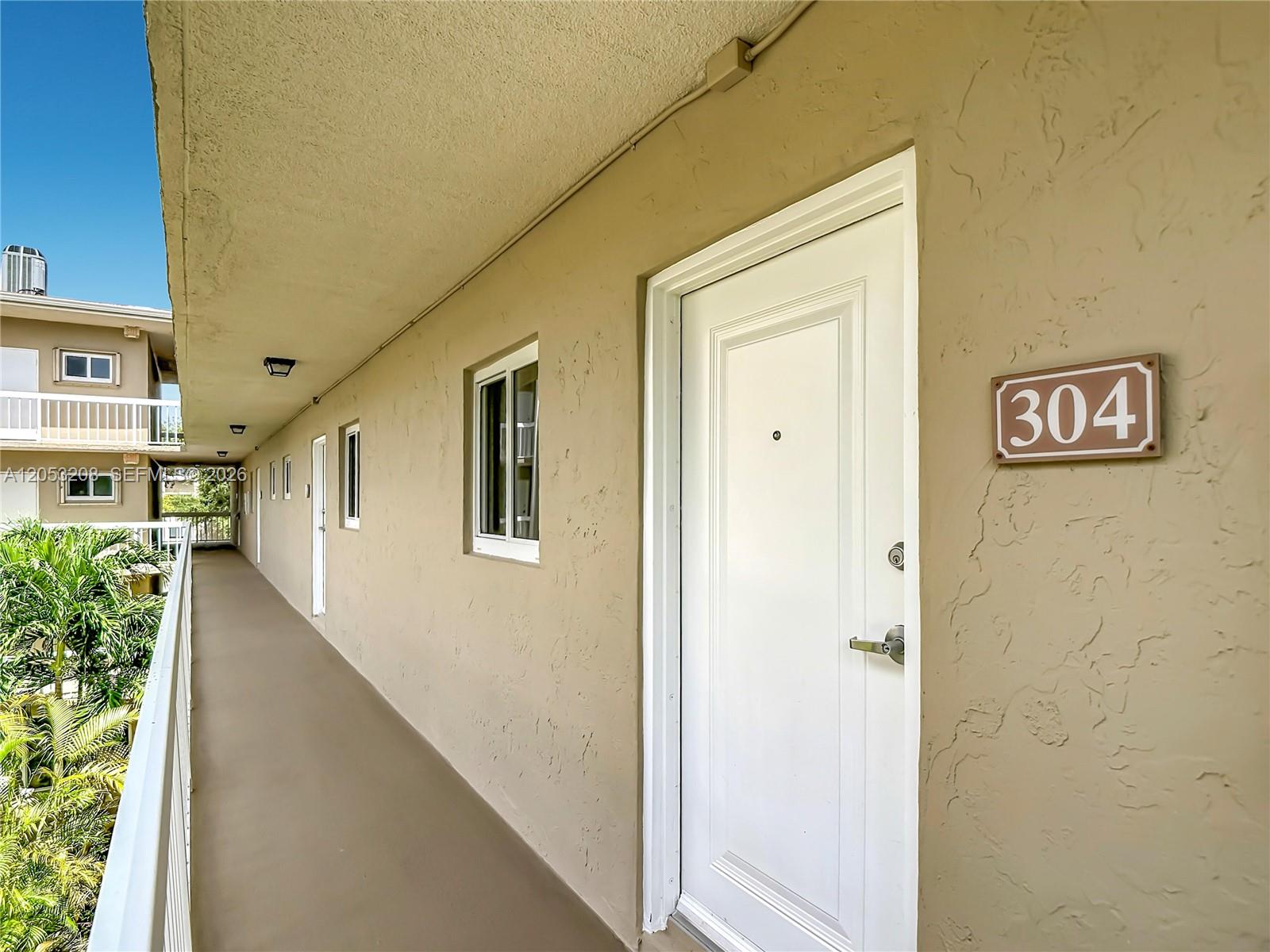An exterior walkway leads to a white door marked with the number 304 — 7722 Camino Real # E304, Miami FL 33143, MIAMI, FL