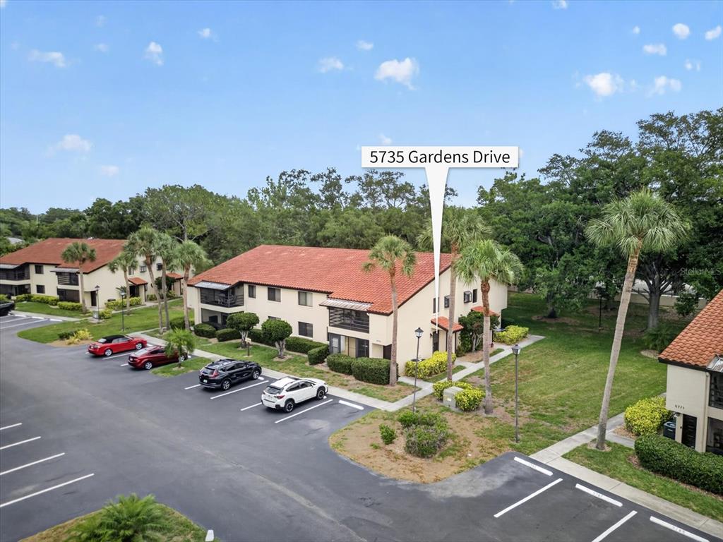 An aerial view shows a two-story apartment building with a red tile roof and parking — 5735 GARDENS DRIVE UNIT 5735, SARASOTA, FL