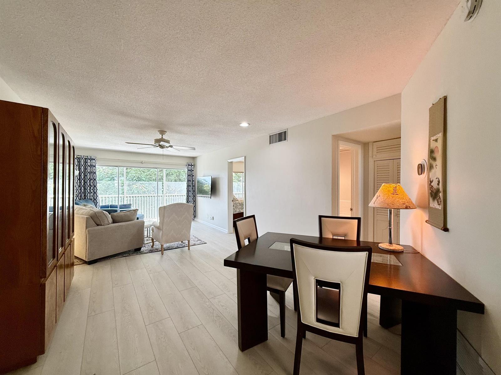 A dining area with a dark table and chairs opens into a living room with balcony — 50 Celestial Way # 305, Juno Beach FL 33408, JUNO BEACH, FL