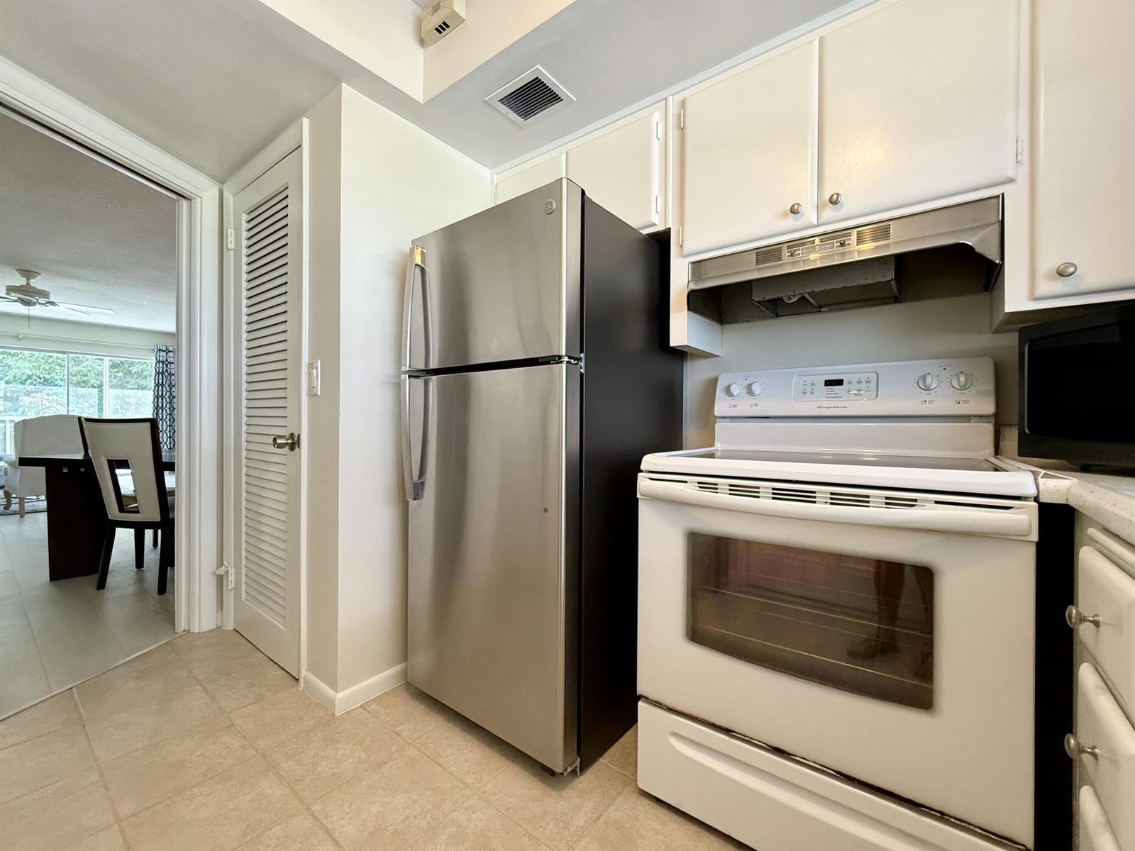 A kitchen features a stainless steel refrigerator, a white stove, and white cabinetry — 50 Celestial Way # 305, Juno Beach FL 33408, JUNO BEACH, FL
